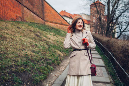 Stylish woman tourist walking enjoying ancient architecture of Wawel Castle in Krakow, Poland in spring. Fashionable lady wearing trendy accessoriesの写真素材