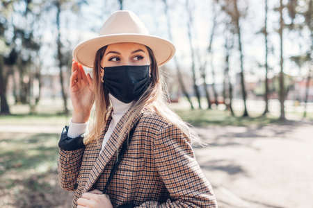 Stylish woman wears reusable mask outdoors during coronavirus covid-19 pandemic in empty spring park.の写真素材