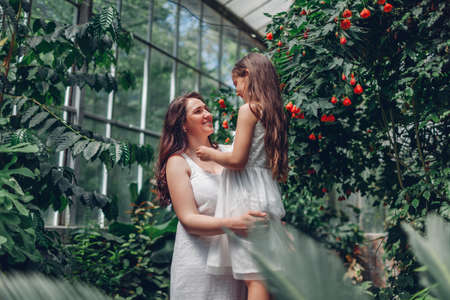 Woman and child walking in botanical garden. Family explore tropical plants and flowers in greenhouse. Mother and daughter talkingの写真素材