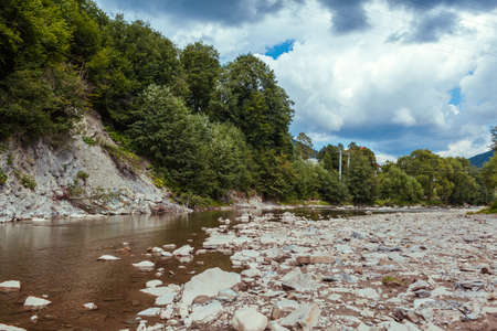 Summer mountain river surrounded with rocks, cliff and trees. Natural landscape background. View of wild natureの写真素材