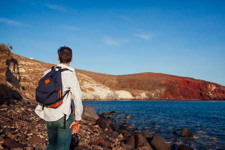 Traveler looking at Red beach landscape in Akrotiri, Santorini island, Greece admiring sea and...