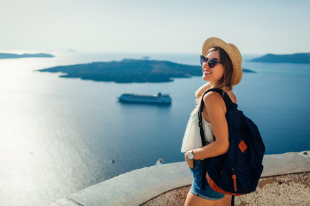 Woman tourist enjoying Caldera sea landscape in Fira, Santorini island looking at Aegean sea and shipsの写真素材