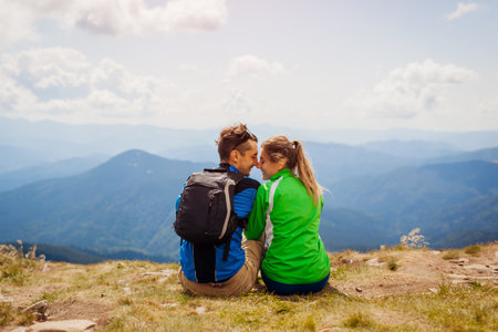 Couple of hikers admire view of Carpathian mountains. Happy tourists hug relaxing on top of Hoverla. Traveling in summer Ukraineの写真素材