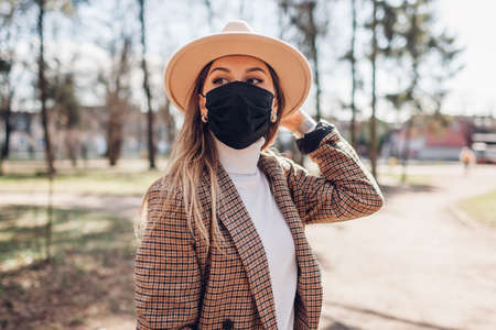 Close up portrait of stylish woman wearing reusable mask outdoors during pandemic in empty park. Spring fashionの写真素材