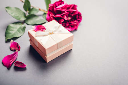 Small gift box with purple rose with present for Valentine's day on grey background. Spaceの写真素材