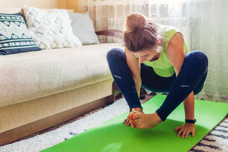 Home yoga workout during virus lockdown. Shoulder pressing pose. Woman training using mat. Arm balancingの写真素材
