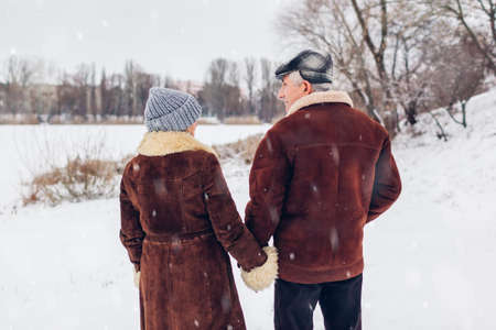 Senior family couple dancing outdoors during snowy winter weather. Elderly people having fun. Valentine's day loveの写真素材