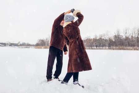 Senior family couple dancing outdoors during snowy winter weather. Elderly people having fun. Valentine's day walkの写真素材