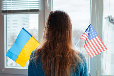 Woman holding ukrainian and american flags during war with Russia. Invasion in Ukraine. 2022 Russian...