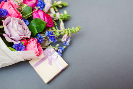 Close up of summer bouquet of roses foxgloves bachelor buttons flowers wrapped in paper and arranged...