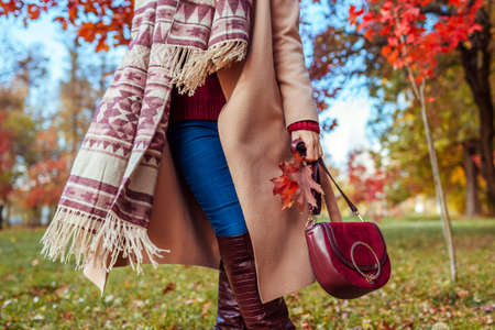 Close up of fashionable stylish clothes shoes and accessories. Woman walking in fall park holding handbag. Autumn female outfit.の写真素材