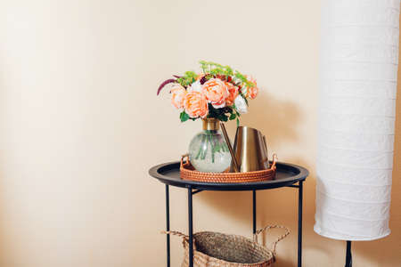 Fresh bouquet of orange english roses flowers put in vase on table with watering can by floor lamp....