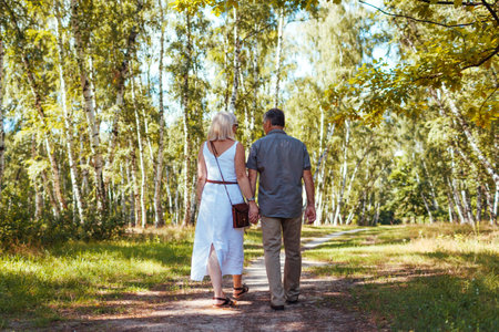 Senior family couple walking outdoors in summer forest. Elderly people holding hands. Romantic dateの写真素材