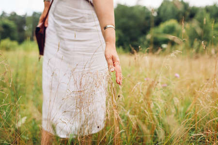 Mental health. Woman walking in meadow feeling harmony with nature and balance touching grass. Healthy lifestyleの写真素材