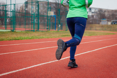 Sportive woman athlete running on sportsground in autumn. Close up of sneakers and female legs on track. Active healthy lifestyleの写真素材