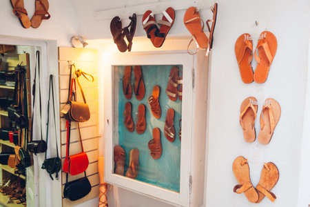 Display of shoes store. Summer sandals and handbags hanging on wall. Leather handmade flats in retro rustic styleの写真素材