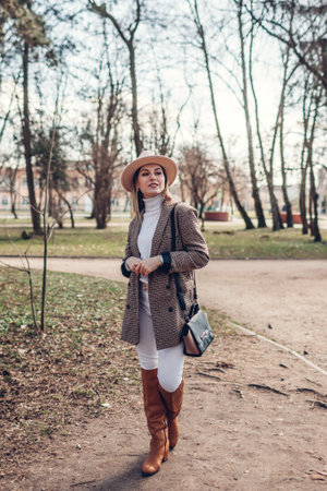 Full body portrait of beautiful woman wearing stylish blazer, hat and boots in spring park. Female fashion. Modern clothes and accessoriesの写真素材