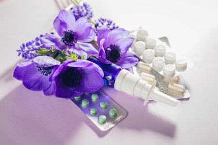 Seasonal spring allergy background. Pills and nasal spray flat lay with purple flowers. Pollen allergen.の写真素材
