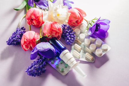 Seasonal spring allergy. Antihistamine pills and nasal spray flat lay with purple pink flowers. Healthcare for allergic.の写真素材