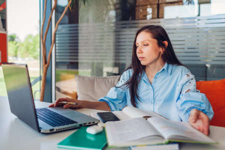 Young businesswoman working online in office using laptop. Middle-aged woman teacher searching for...