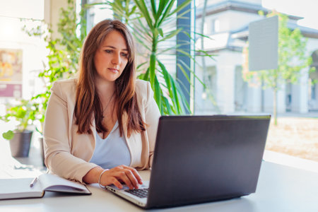 Young female teacher getting ready for lesson working in office using laptop computer. business woman typing. Working online in modern workspaceの写真素材