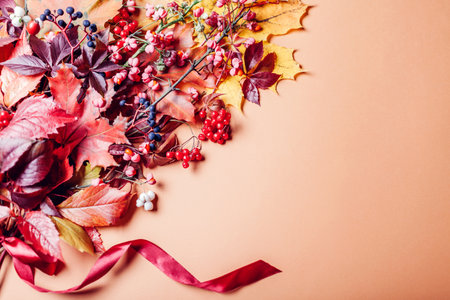 Fall bouquet of yellow red orange leaves and berries arranged on brown background with ribbon. Autumn decor arrangement. Spaceの写真素材