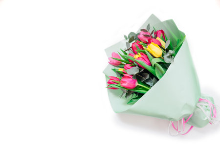 Spring flowers. Women's day background. Bouquet of yellow and pink tulips with ribbon. Present gift for Mother's day. Space. Top viewの写真素材