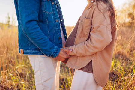 Future father and mother holding hands. Pregnant family couple walking outdoors at sunset. Parenthoodの写真素材