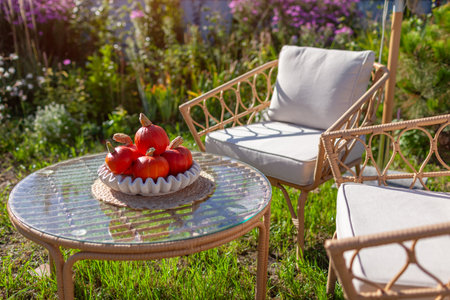 Glass table decorated with bowl full of small pumpkins in fall garden. Autumn season. Outdoor furniture for terrace and patio lounge areasの写真素材