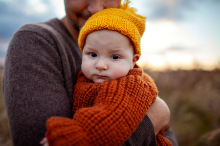 Close up portrait of little baby girl on fathers hands. Loving dad holding his daughter outdoors. Infant wears warm fall clothesの写真素材