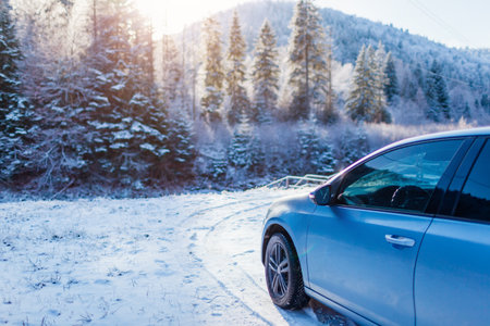 Traveling in winter by car. Holiday trip to snowy mountains. Blue auto stopped by frozen forest in Carpathians.の写真素材
