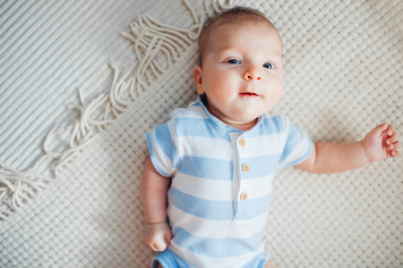 Little newborn baby lying on couch by knitted toy making sounds. Cute surprised infant looking at camera. Top viewの写真素材