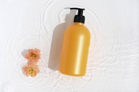Cosmetic bottle on white background with water and flowers. Top view, closeupの写真素材