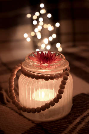 Burning candle with flower on a brown plaid   with garland.の写真素材
