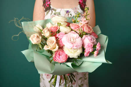 Woman holding a beautiful bouquet with flowers on green background. Front view. Valentines, womens, mothers day, love concept. 8th of march. 14th of february.の写真素材