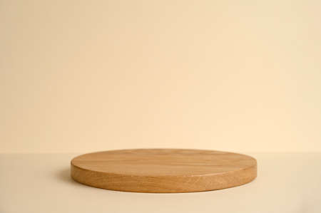 Round wooden podium on beige background for product presentation. Front view. Copy space.の写真素材
