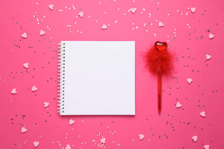 White empty sheet in notebook on a pink background with hearts next to the pen. Copy space. Place to your text. Valentines day, love concept. Top view.の写真素材