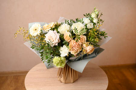 Beautiful flowers in vase on a table with beige background. Womens, mothers day, love concept. Spring, summer season. Front view.の写真素材