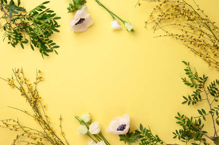 Frame of green branches and leaves on yellow background. Spring, summer concept. Flat lay, top view, copy space.の写真素材