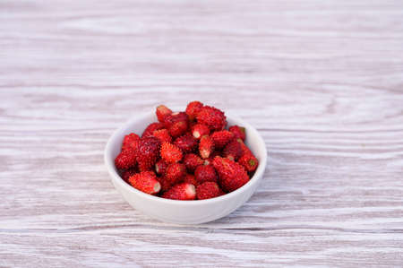 Fresh ripe strawberries in white bowl, on wooden tableの写真素材