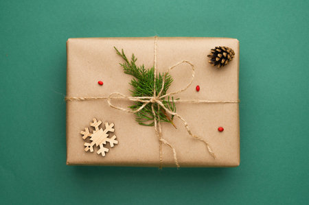 Christmas composition with kraft gift box with coniferous branches, wooden snowflake on green background.の写真素材