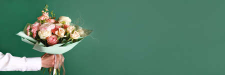 Man holding and giving a beautiful bouquet with flowers to woman on green background. Front view. Valentines, womens, mothers day, love concept. Bannerの写真素材