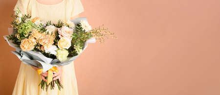Woman holding a beautiful bouquet with flowers on beige background. Front view. Valentines, womens, mothers day. Autumn, summer concept. Bannerの写真素材