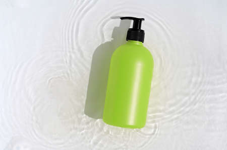 Cosmetic bottle on white background with water and flowers. Top view, closeup.の写真素材