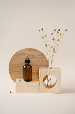 Cosmetic in a glass bottle on stone podium, dried flower on beige background. Front view.の写真素材