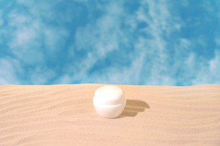 Cosmetic jar on sandy podium against sky background with clouds. Concept of cosmetic products. Front view. Desigh for you productの写真素材