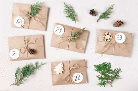 Christmas advent calendar. Flat lay with kraft envelopes with gifts, fir branches, pine cones. Top...