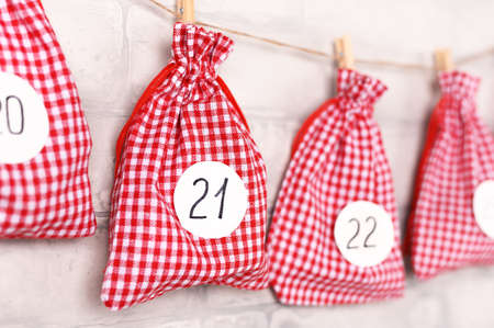 Christmas advent calendar. Gift bags hanging on white brick wall. December concept. Selective focus.の写真素材