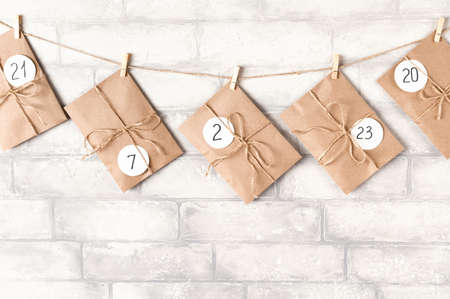 Christmas advent calendar. Craft envelopes hanging on white brick wall. December concept.の写真素材