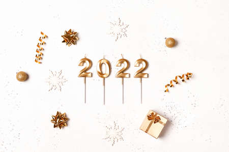 Christmas frame with golden decorations on white background with festive golden numbers 2022 made of...